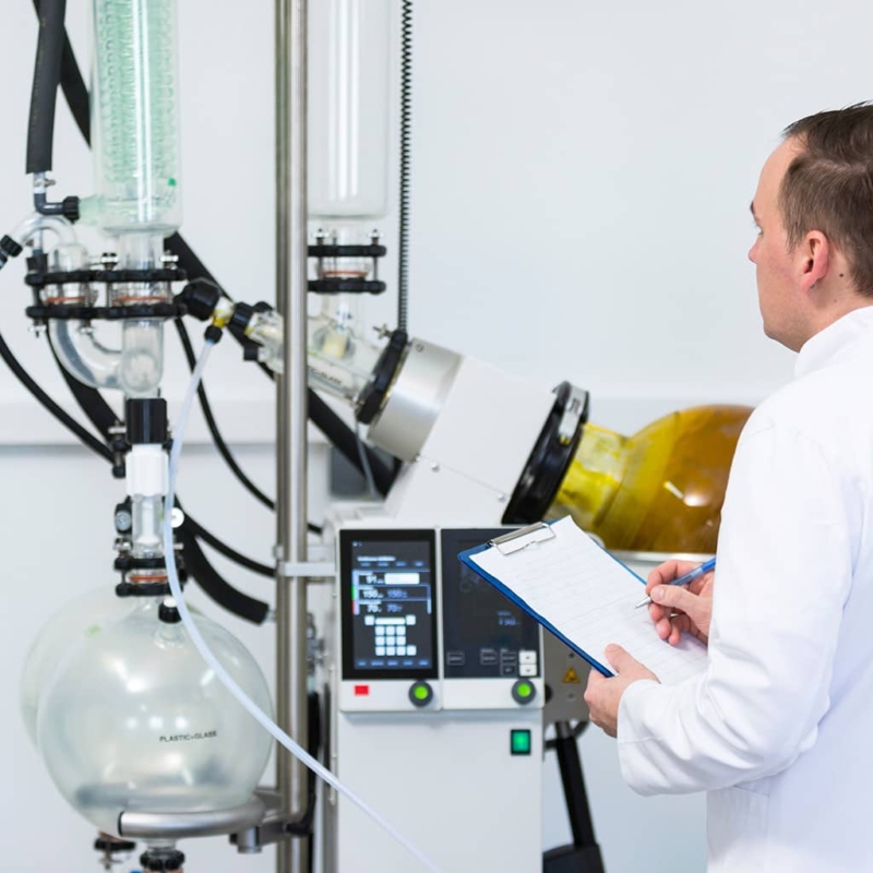 Lab tech controlling rotavapor machine during CBD oil extraction