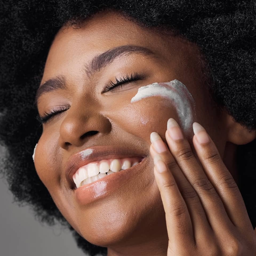 The face of a smiling African model who is applying hemp face cream